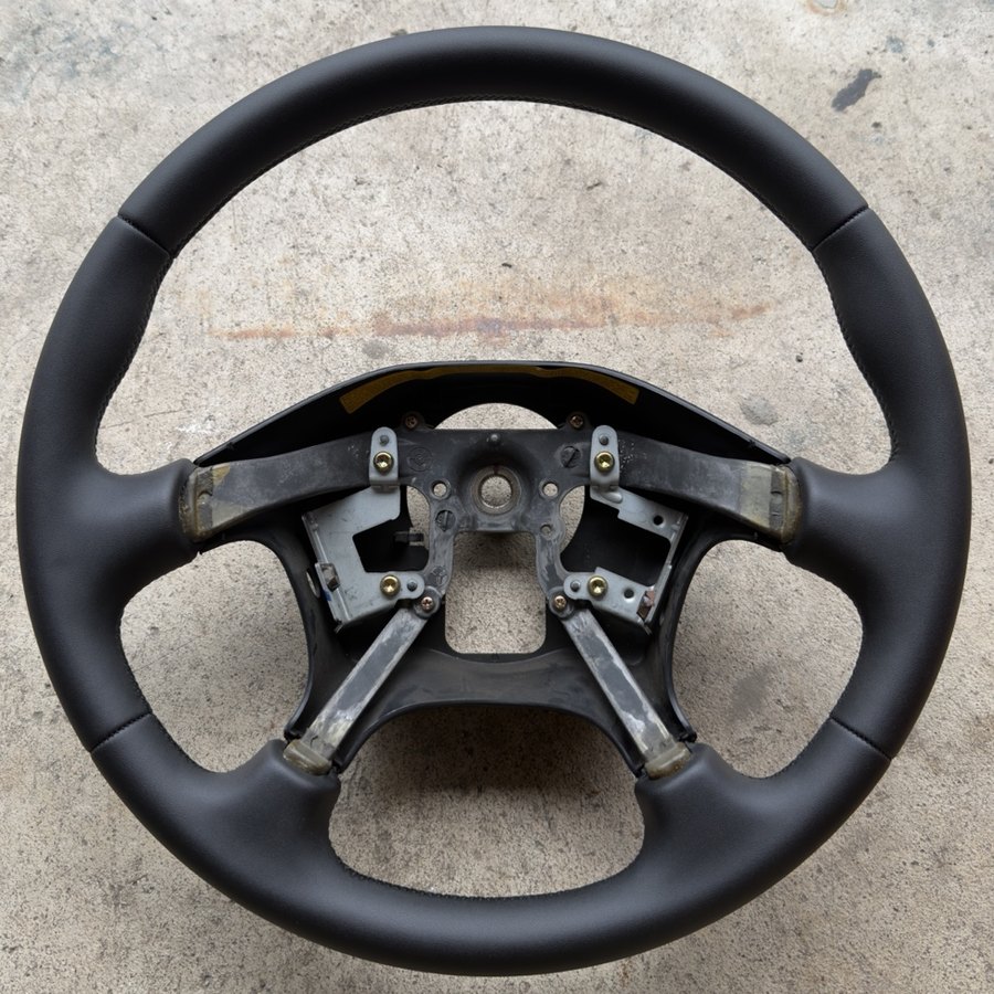 Four-spoke steering wheel rewrapped in smooth black material