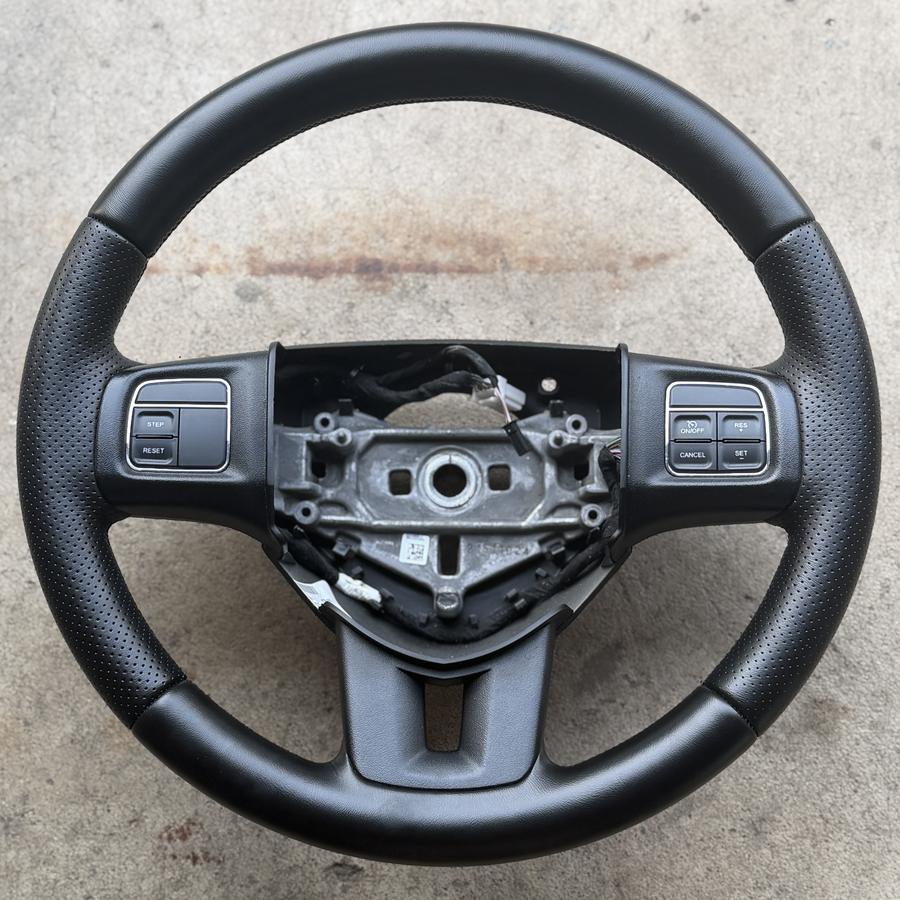 Steering wheel with cruise control buttons, perforated grip areas